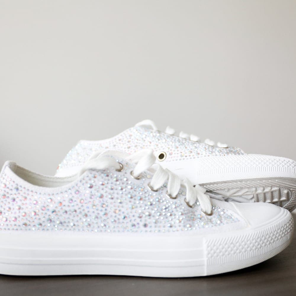Par de zapatillas blancas con detalles brillantes sobre fondo neutro